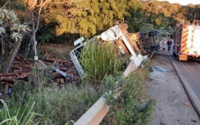 Motorista fica ferido após carreta com toras tombar